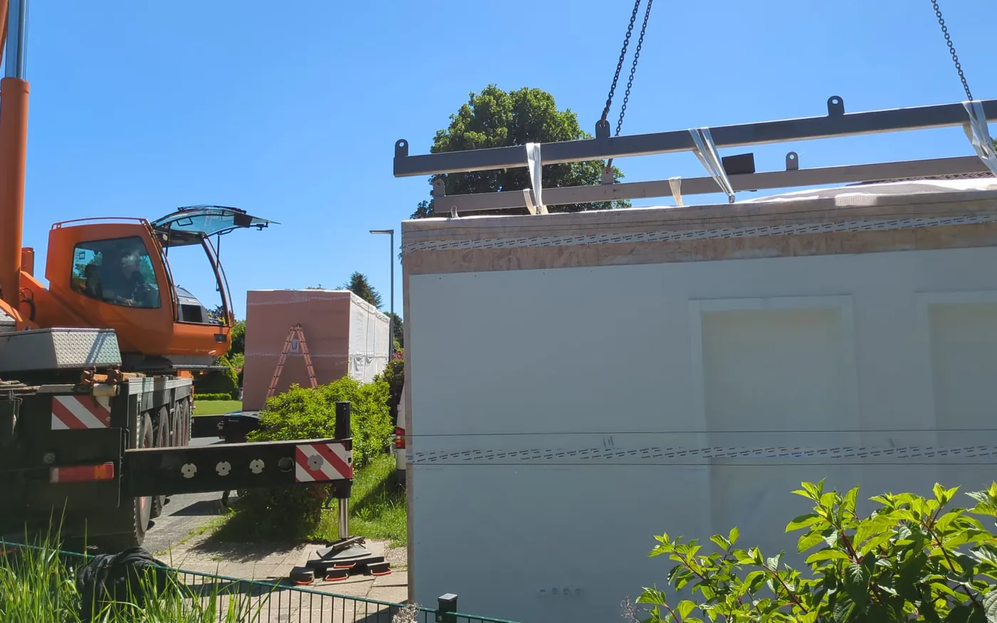 Mobilkran hebt ein vorgefertigtes Wandelement an ein Bestandsgebäude